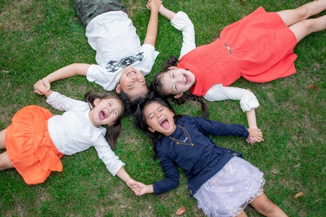 芝生の上で手をつなぐ子供たち