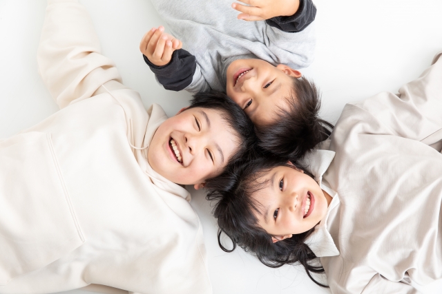 床に寝転ぶ笑顔の親子三人